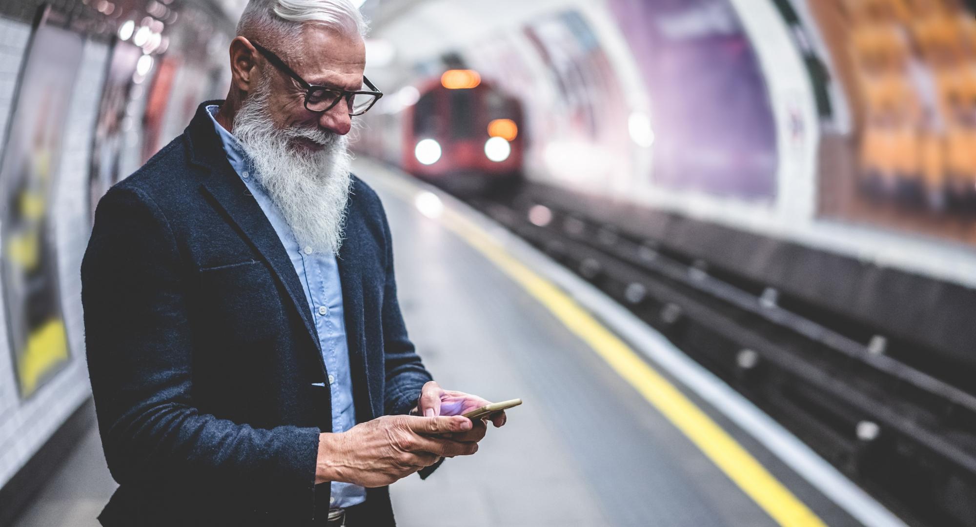 Male rail passenger at a station using a smartphone