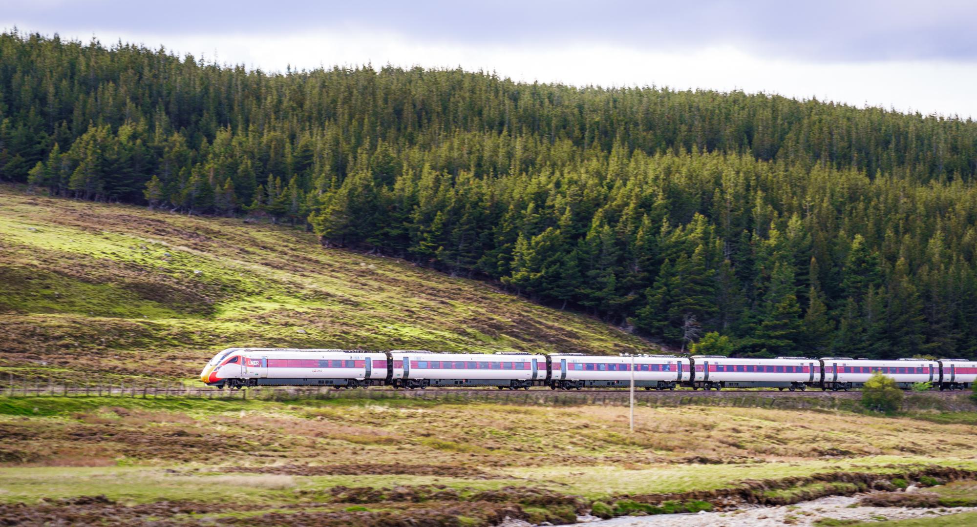 Side view of an LNER Azuma high speed train travelling at speed along a hillside in the Scottish Highlands